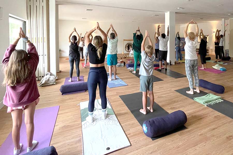 A class in progress in one of the studios at the Yoga Center, students standing with arms raised