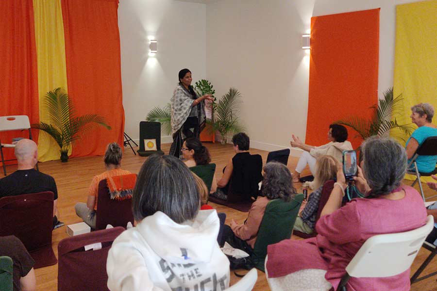 A talk in one of the rooms at the Yoga Center, the audience seated on cushions and chairs before a speaker